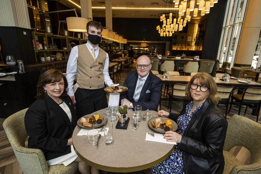 Northern Ireland Economy Minister Diane Dodds (left) welcomes the reopening of indoor hospitality at the Grand Central Hotel in Belfast with Janice Gault (right) of the Northern Ireland Hotels Federation (NIHF) and General Manager Stephen Meldrum (second from right) as they are being served the hotel's house breakfast by Conor Sullivan.