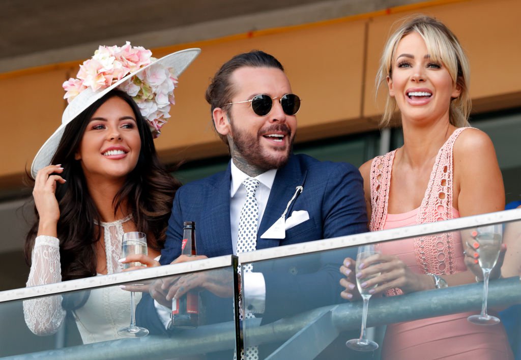 Shelby Tribble, Pete Wicks and Olivia Attwood watch the racing as they attend day 3 'Ladies Day' of Royal Ascot at Ascot Racecourse