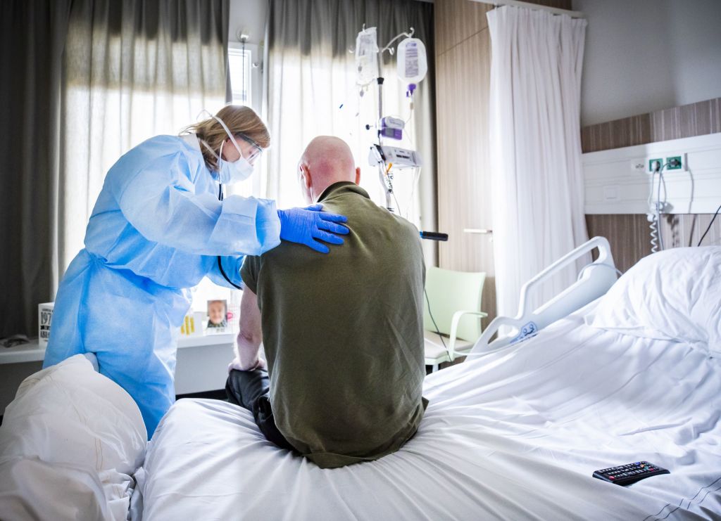 A nurse in full protective gear cares for a COVID-19 patient