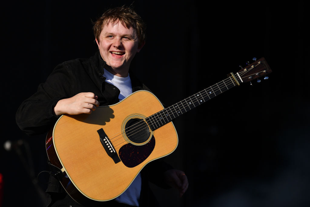 Lewis Capaldi on stage at his concert, holding his guitar