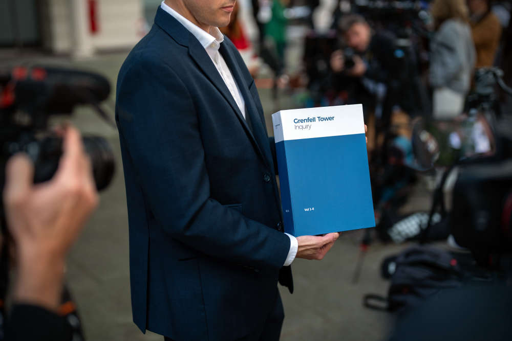 A member of inquiry staff poses with a copy of the Grenfell Tower Report outside the building where the Grenfell Inquiry is taking place, on September 4, 2024 in London, England.